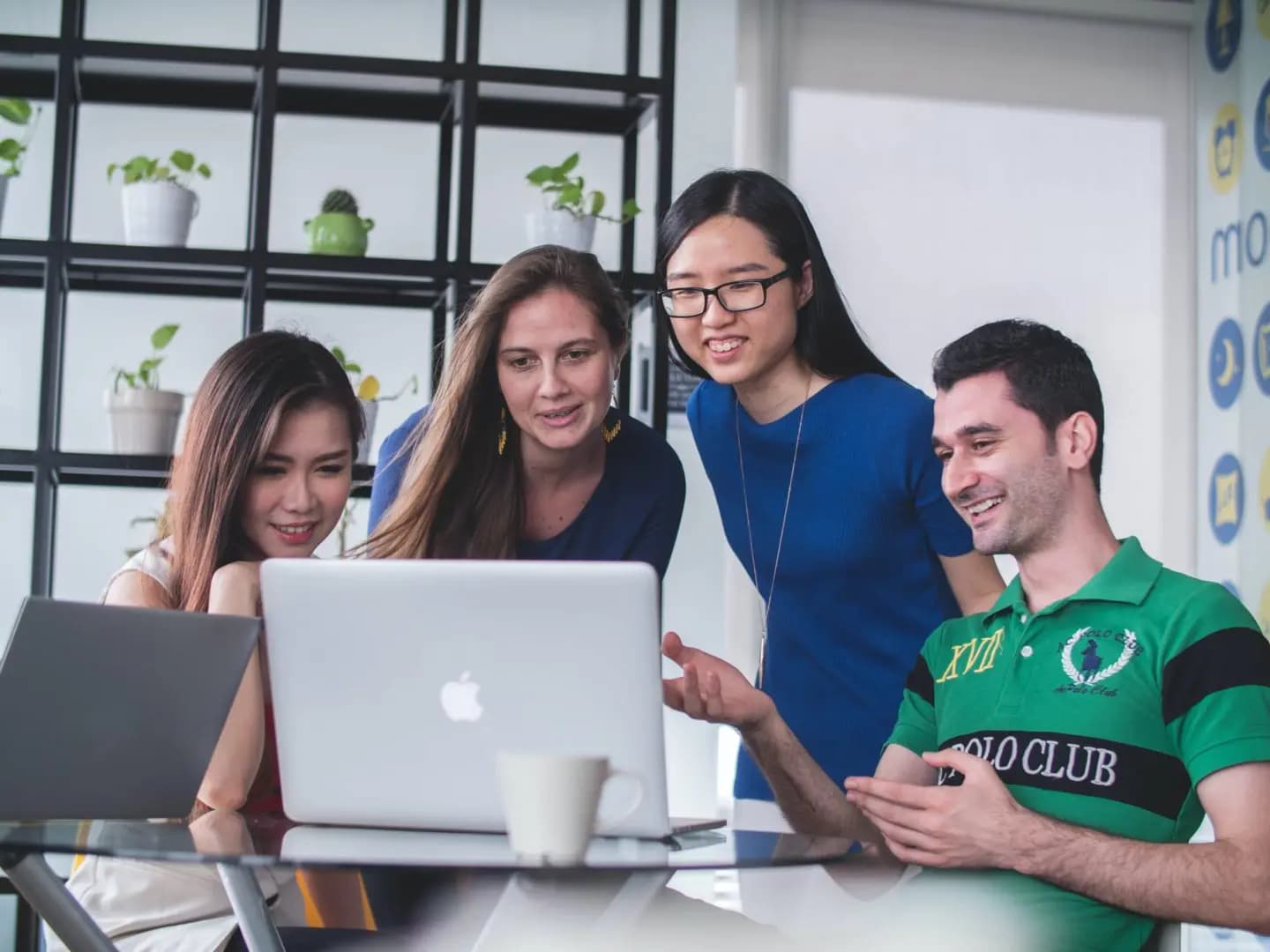 Photograph of four people gathered around a laptop