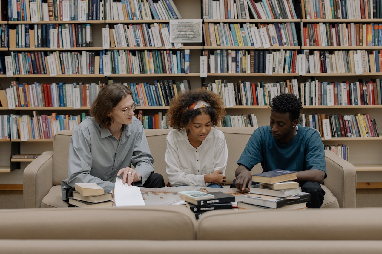 A group of students sitting on a sofa reading books